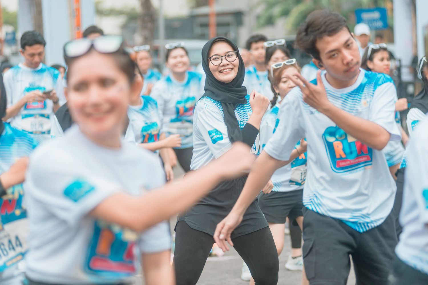 Large group of participants wearing matching white and blue t-shirts celebrate together at an outdoor event.