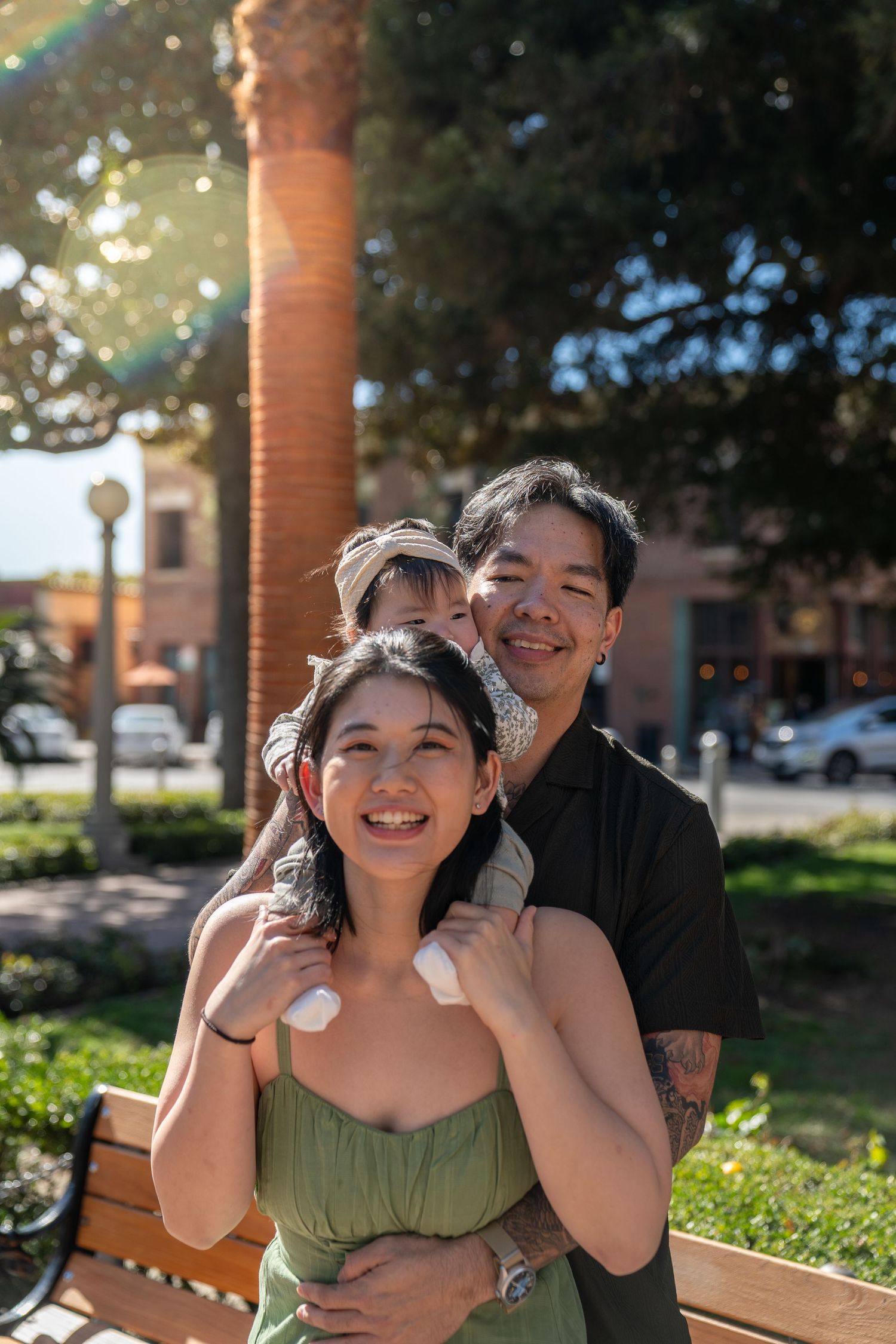 A couple shares joyful moments together outdoors on a sunny day with palm trees in the background.
