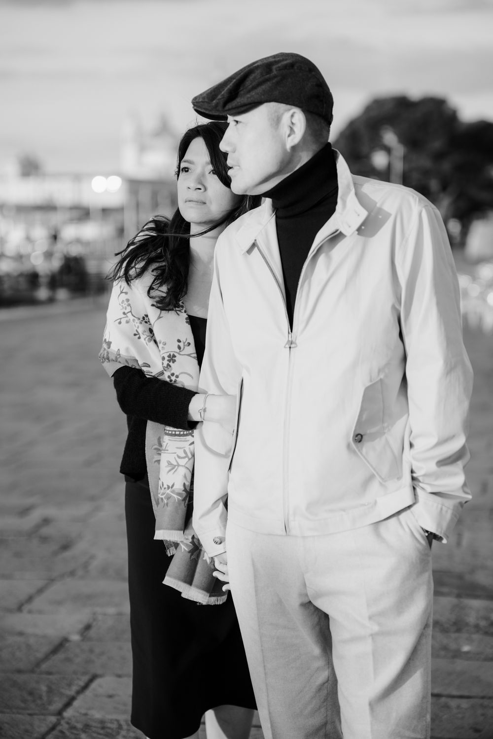 Black and white photos show a couple in contrasting outfits embracing on a beach during a romantic photoshoot.