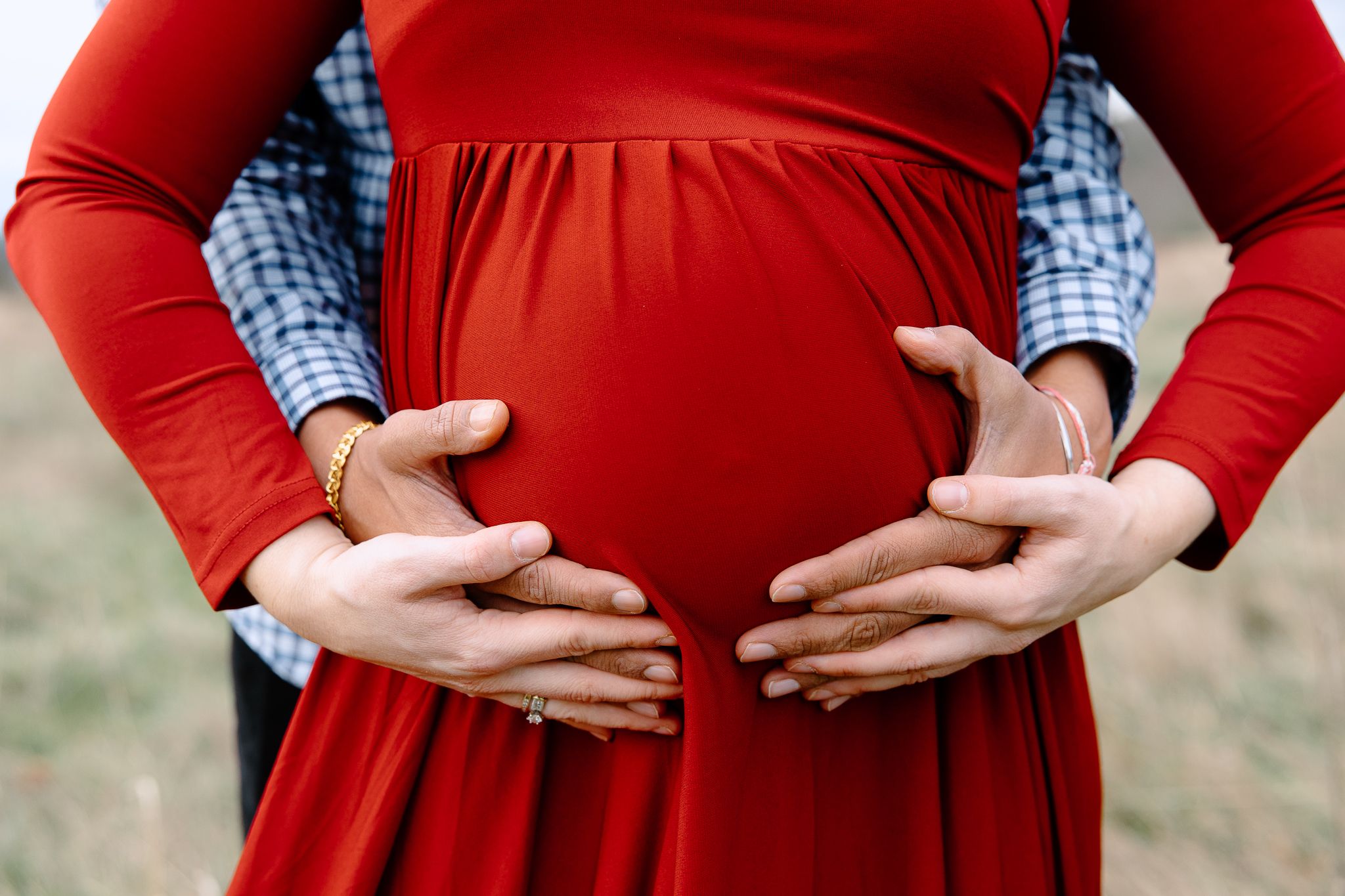 A progression of maternity photos showing a growing baby bump in a red sweater against a blurred outdoor background.