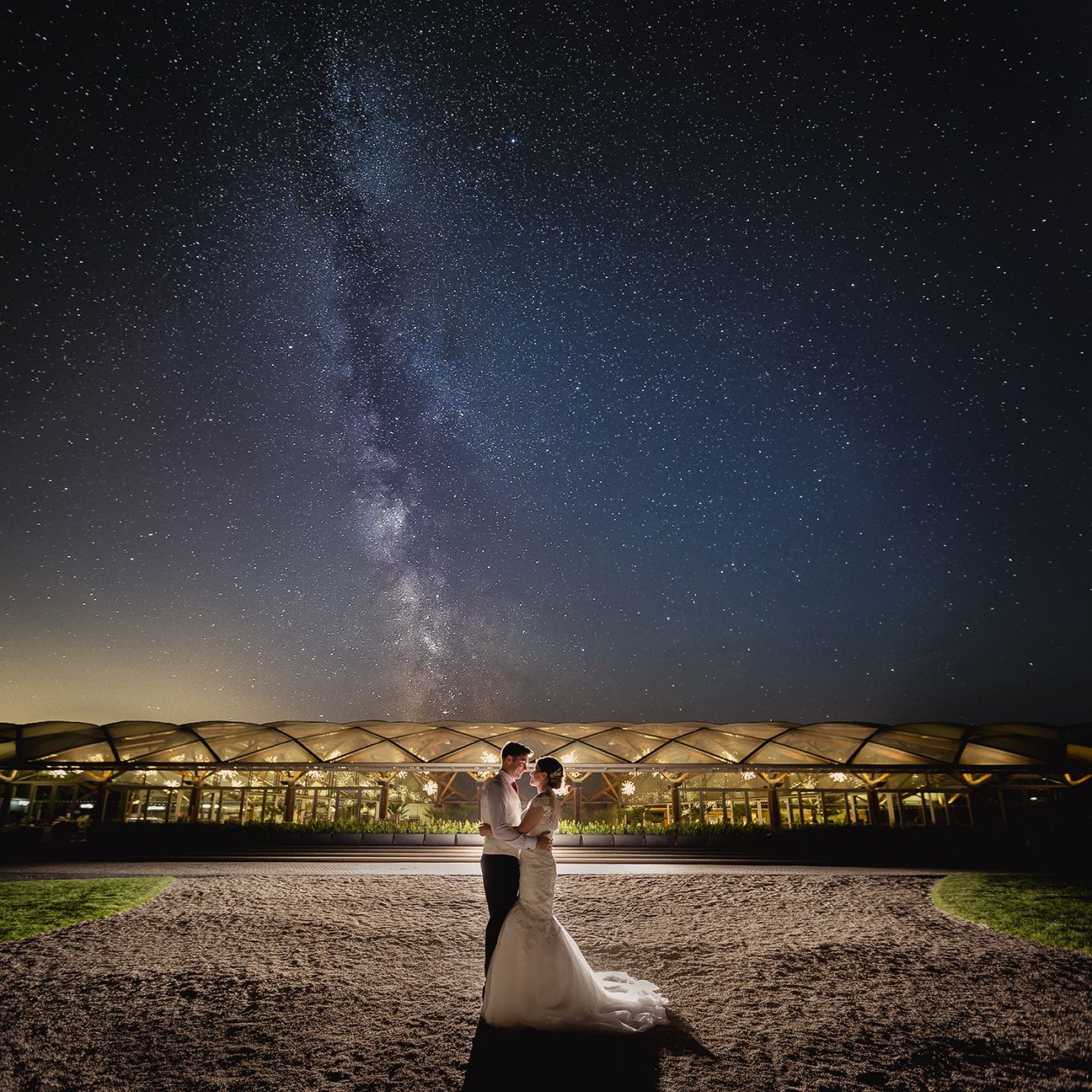 Stunning night sky with Milky Way galaxy visible over rows of empty chairs set up for an outdoor wedding ceremony.
