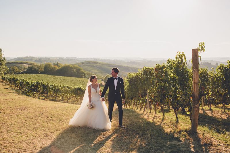 couple walking through vineyard in piedmont destination wedding