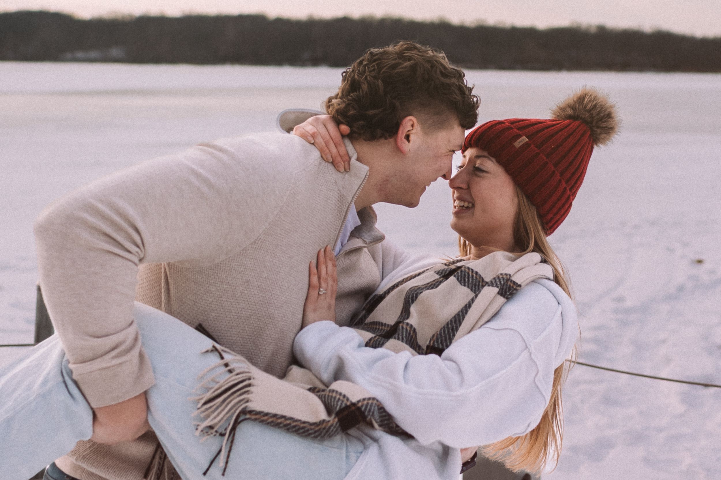 A couple shares a tender moment together lying in the snow during winter.