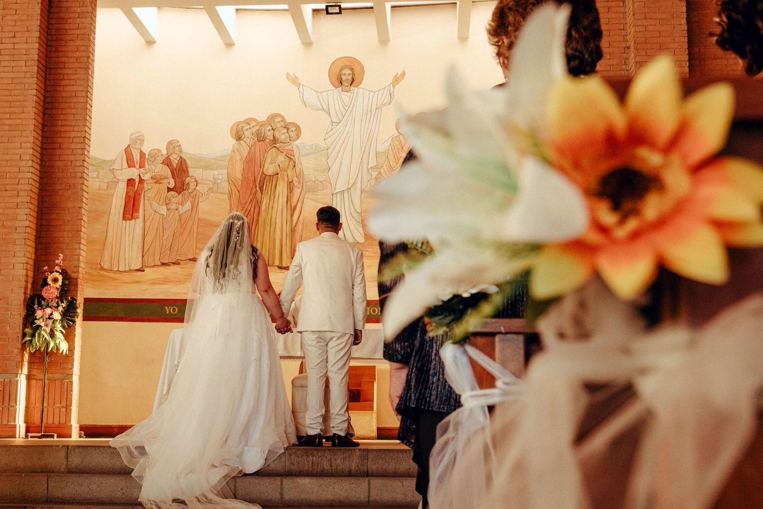 Preparación de ceremonia de matrimonio con arreglos florales y decoración blanca en elegante lugar interior.