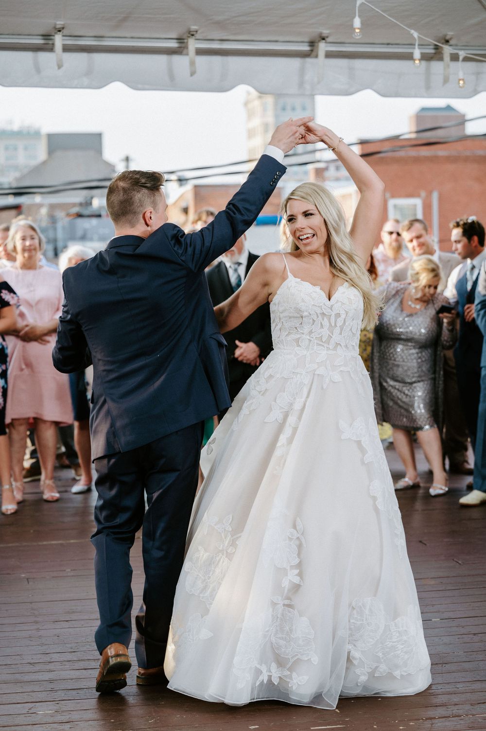 Wedding couple performs romantic dance moves on wooden deck during reception celebration.