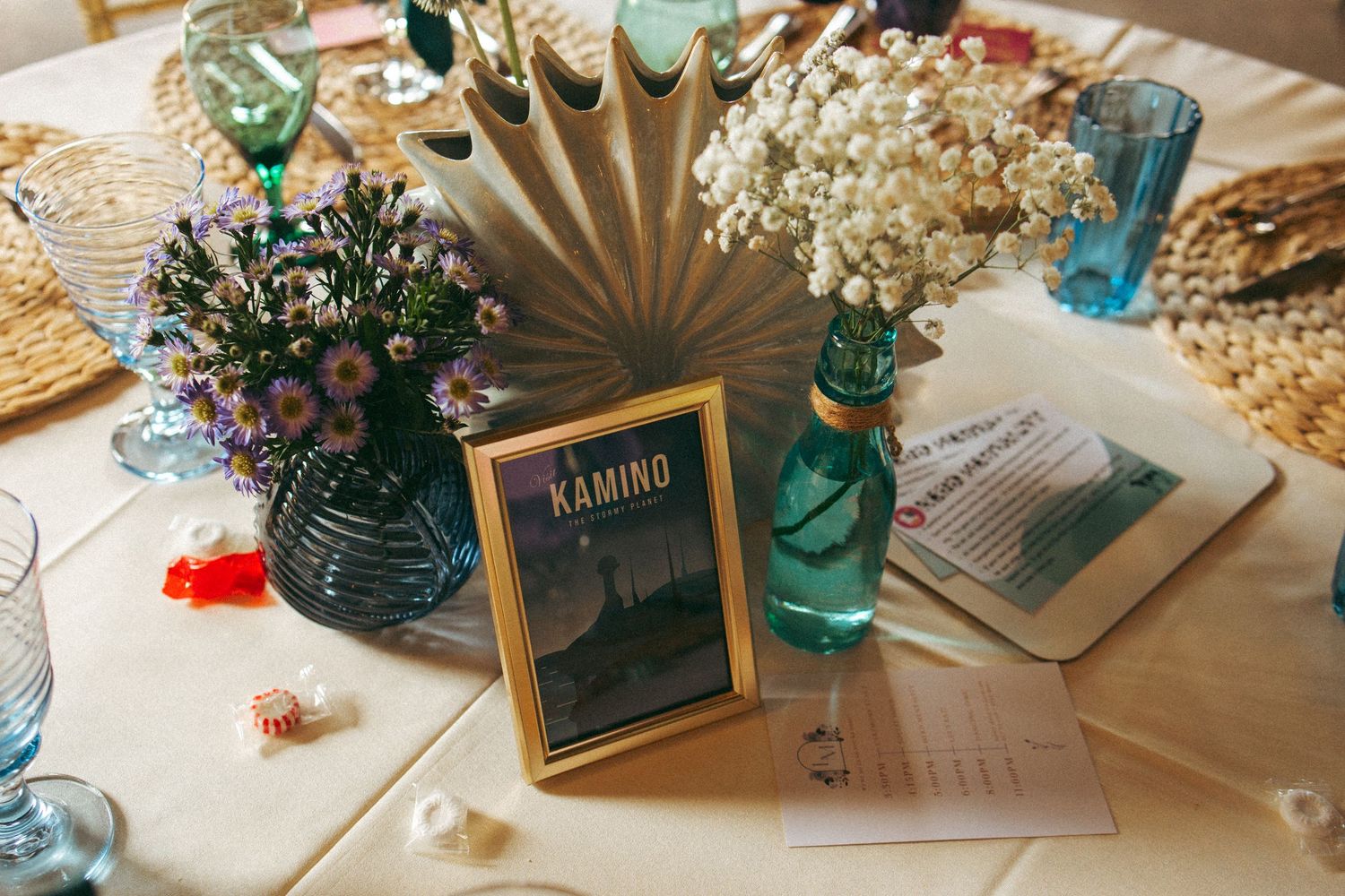 Star Wars themed wedding table centerpiece with Kamino sign, dried flowers, and blue glassware.