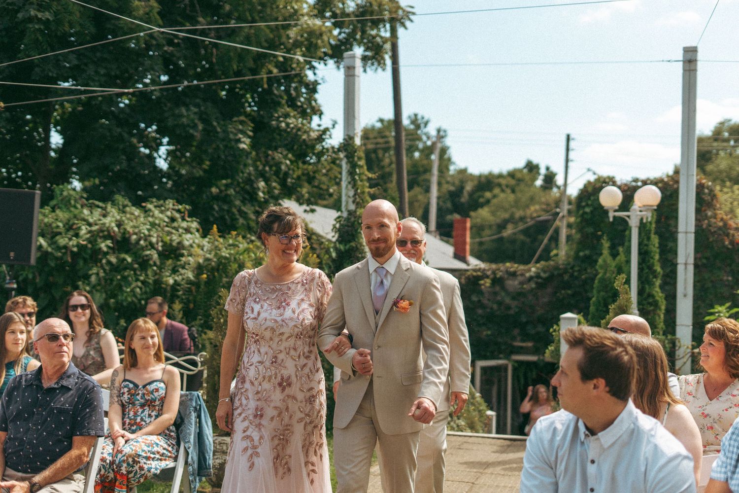 Couple walking down the aisle together at an outdoor garden wedding ceremony with seated guests.