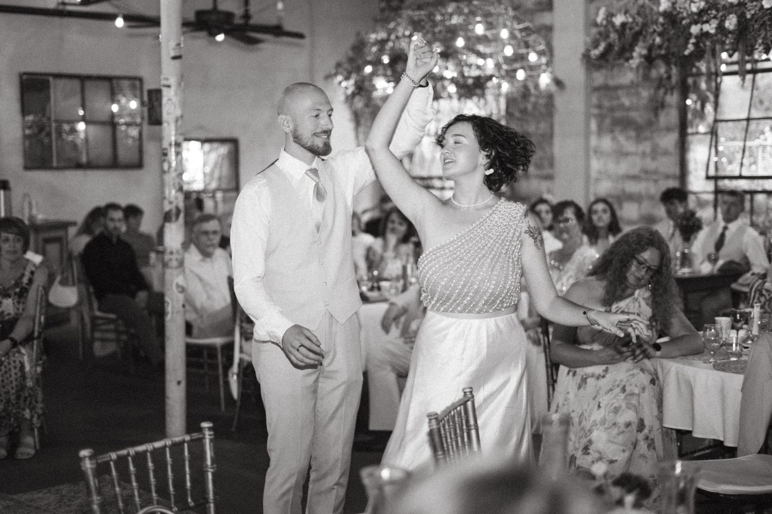 Black and white photo of joyful couple dancing at their rustic wedding reception.