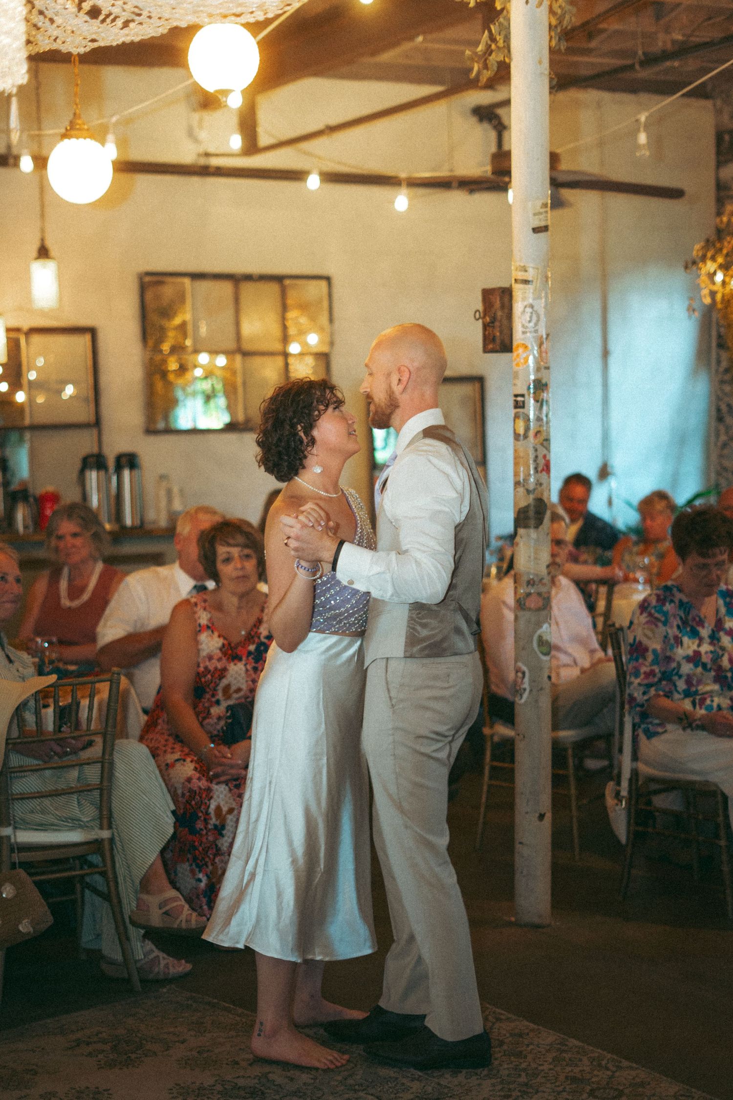 Newlyweds sharing an intimate first dance barefoot at their rustic wedding reception.