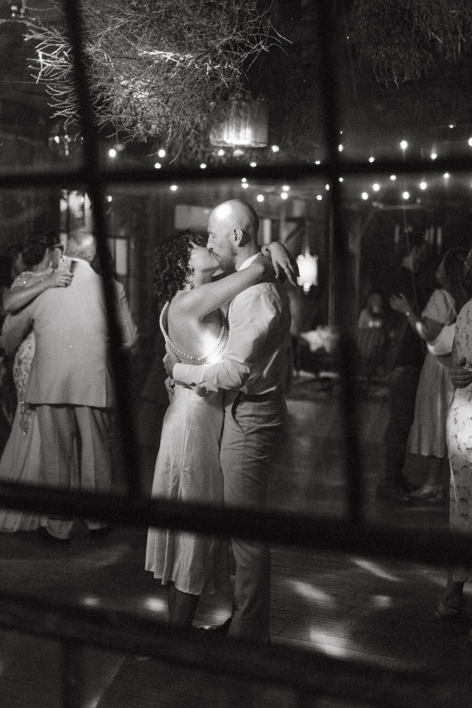 Black and white photo of couple embracing on outdoor dance floor at night wedding.