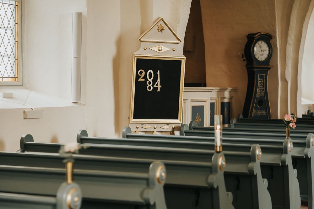 Interior view of a historic church with wooden pews, stained glass windows, and ornate architectural details.