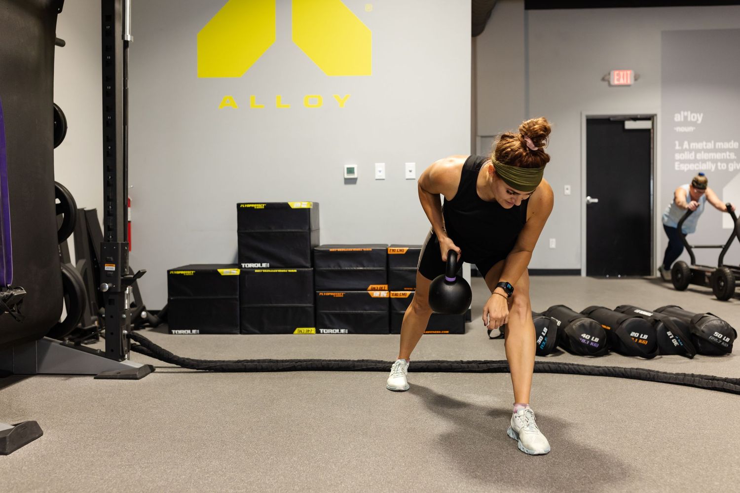 A person performs a lateral lunge exercise in a gym setting with black rubber flooring and white walls. Vanessa Phillips -Alloy Social Media