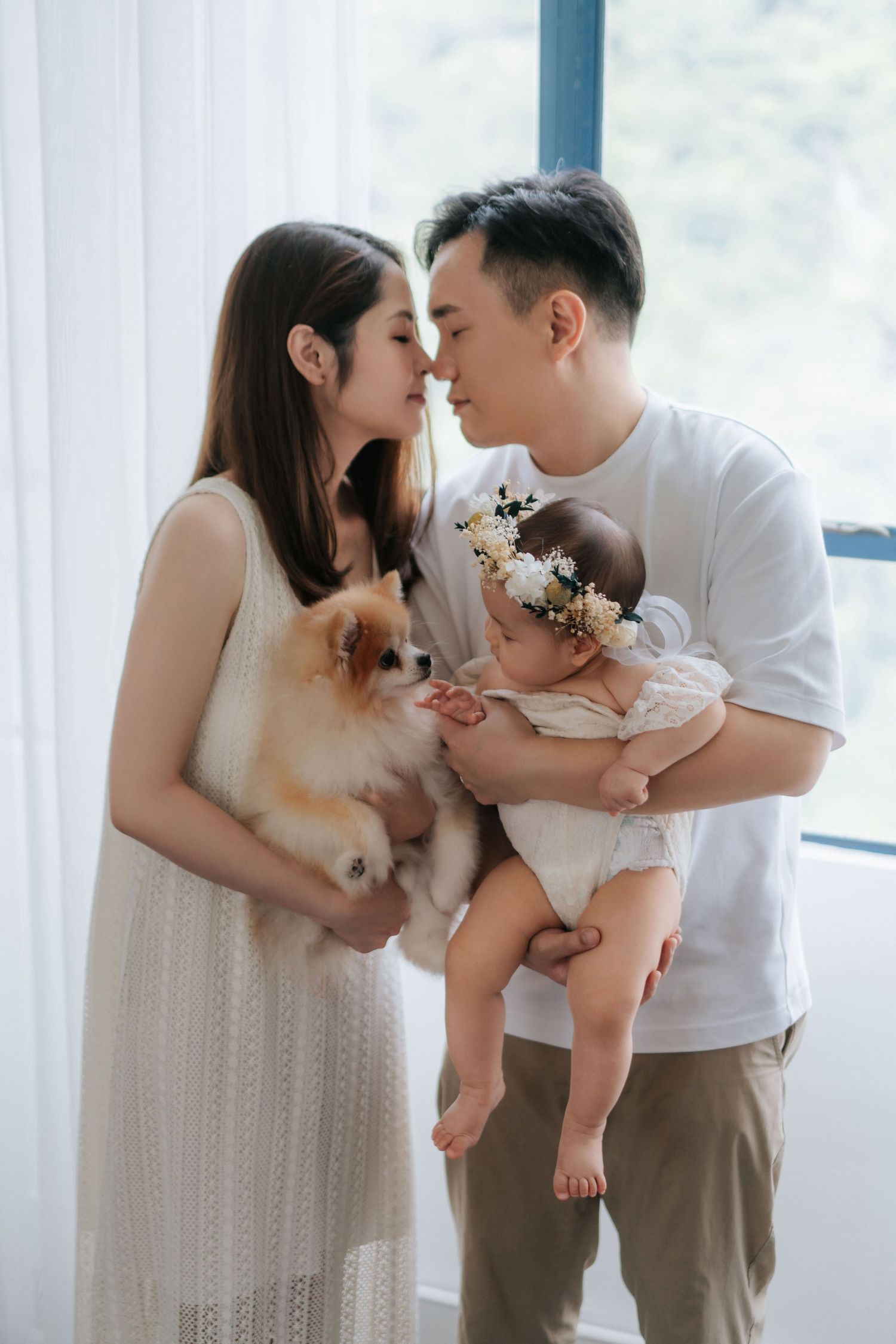 Family shares tender moments together in a bright room with white curtains and neutral tones.一家人在明亮的房間裡共享溫馨時光，房間裡掛著白色窗簾，色調柔和。