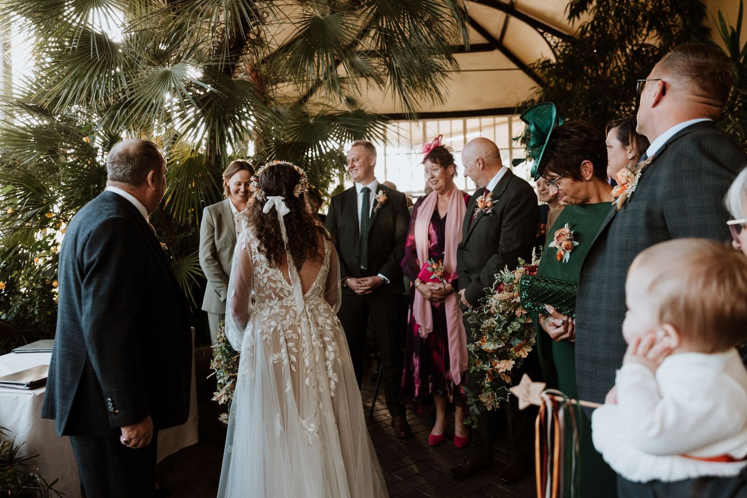 Wedding guests gather for an emotional ceremony moment in an intimate indoor venue with natural lighting.