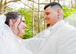 A couple shares a romantic moment in a sun-drenched forest setting during their wedding photoshoot.