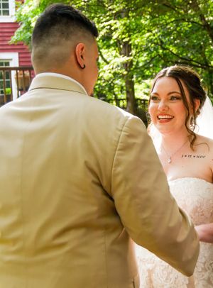 Romantic first look sequence between newlyweds with the groom in a tan suit outdoors.