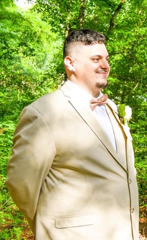A person in a tan suit jacket poses against a lush green forest backdrop in a series of connected photos.