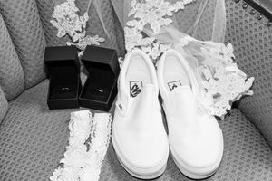 White bridal shoes lined up in a row on a textured gray surface with lace details.