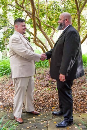 A sequence of four photos showing two people in contrasting suits interacting in a wooded outdoor setting.