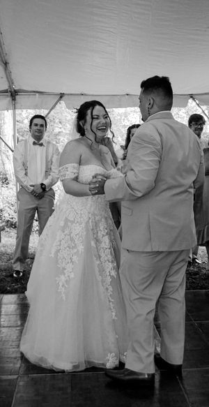 A joyful first dance moment under a white tent during a wedding reception.