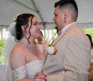 A tender moment shared between newlyweds under a white tent during their wedding celebration.