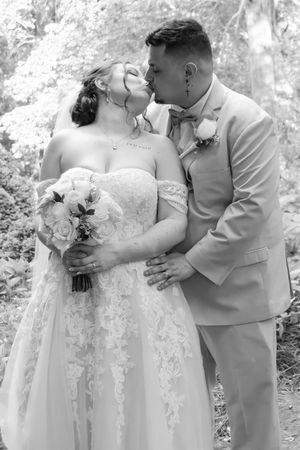 Black and white portrait of a romantic wedding couple sharing an intimate moment with bouquet.