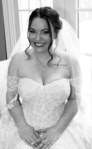 Black and white portrait of a smiling bride in a strapless lace wedding gown with veil.