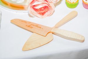 Wooden cake server spatulas with coral and pink floral decorative elements.