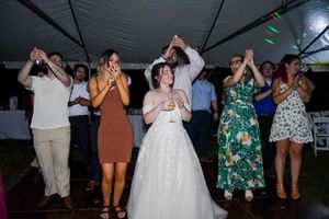 Wedding reception dance floor with guests celebrating under a dark tent canopy.