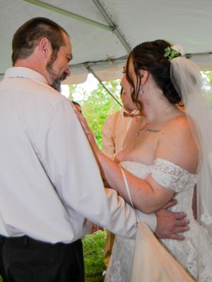 Couple shares intimate first dance moment under white tent during outdoor wedding reception.