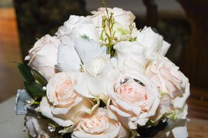 An elegant bridal bouquet featuring blush pink and white roses with delicate greenery accents.