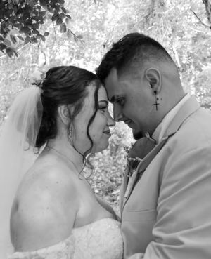A romantic black and white wedding photo showing a tender moment between newlyweds with their foreheads touching.