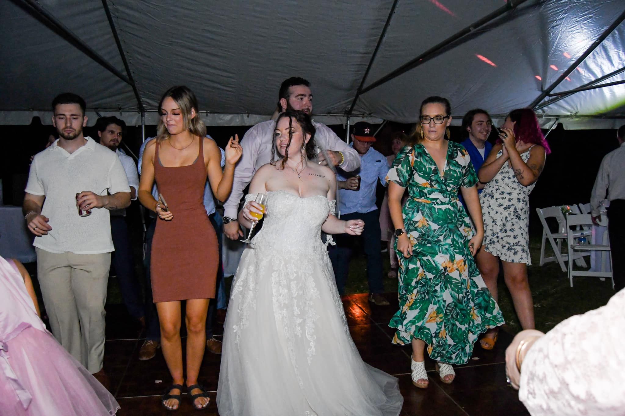 Wedding reception guests dancing and celebrating under a dark tent at night.