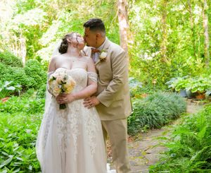 Wedding couple and party members walking along a garden path surrounded by greenery.