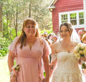 Wedding party walking and laughing together outside a red barn building with white trim.