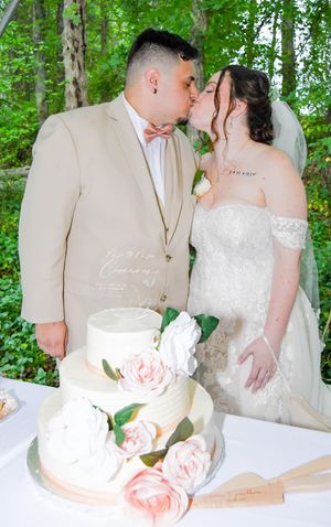 Newlyweds share intimate moments during their woodland wedding ceremony while cutting a delicate pink rose decorated cake.