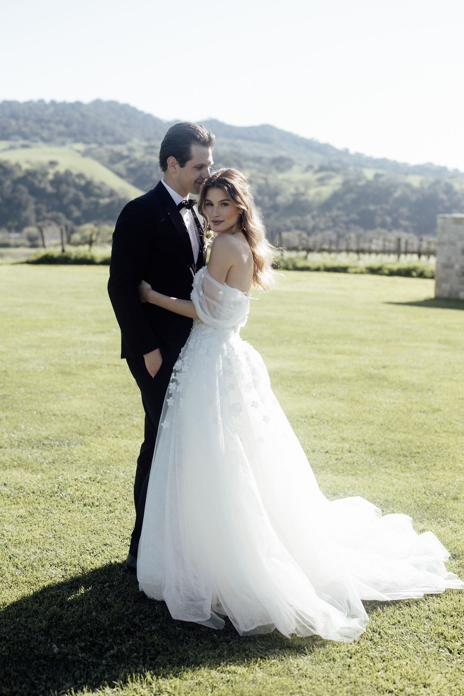 A bride in a flowing white wedding gown twirls gracefully on stone pavement, creating a dreamy spinning motion effect.