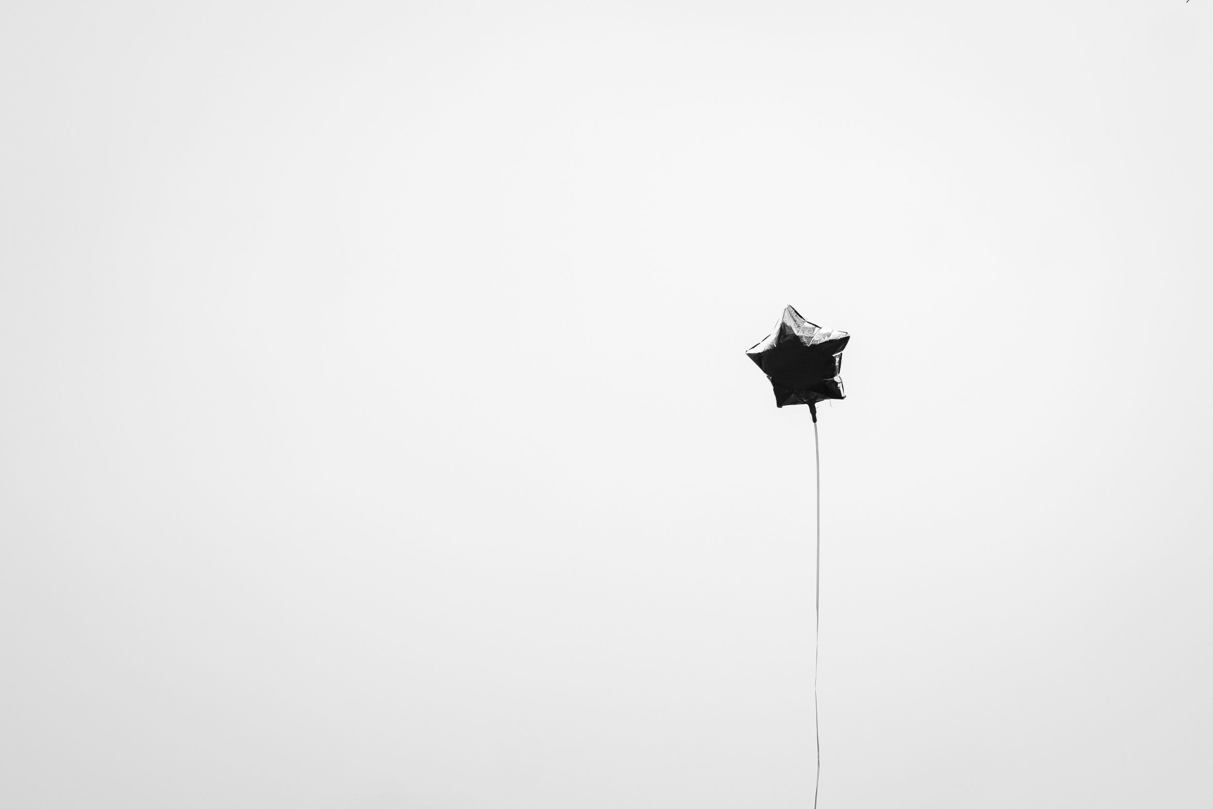 Black graduation cap silhouetted against a bright white background during a celebratory toss.
