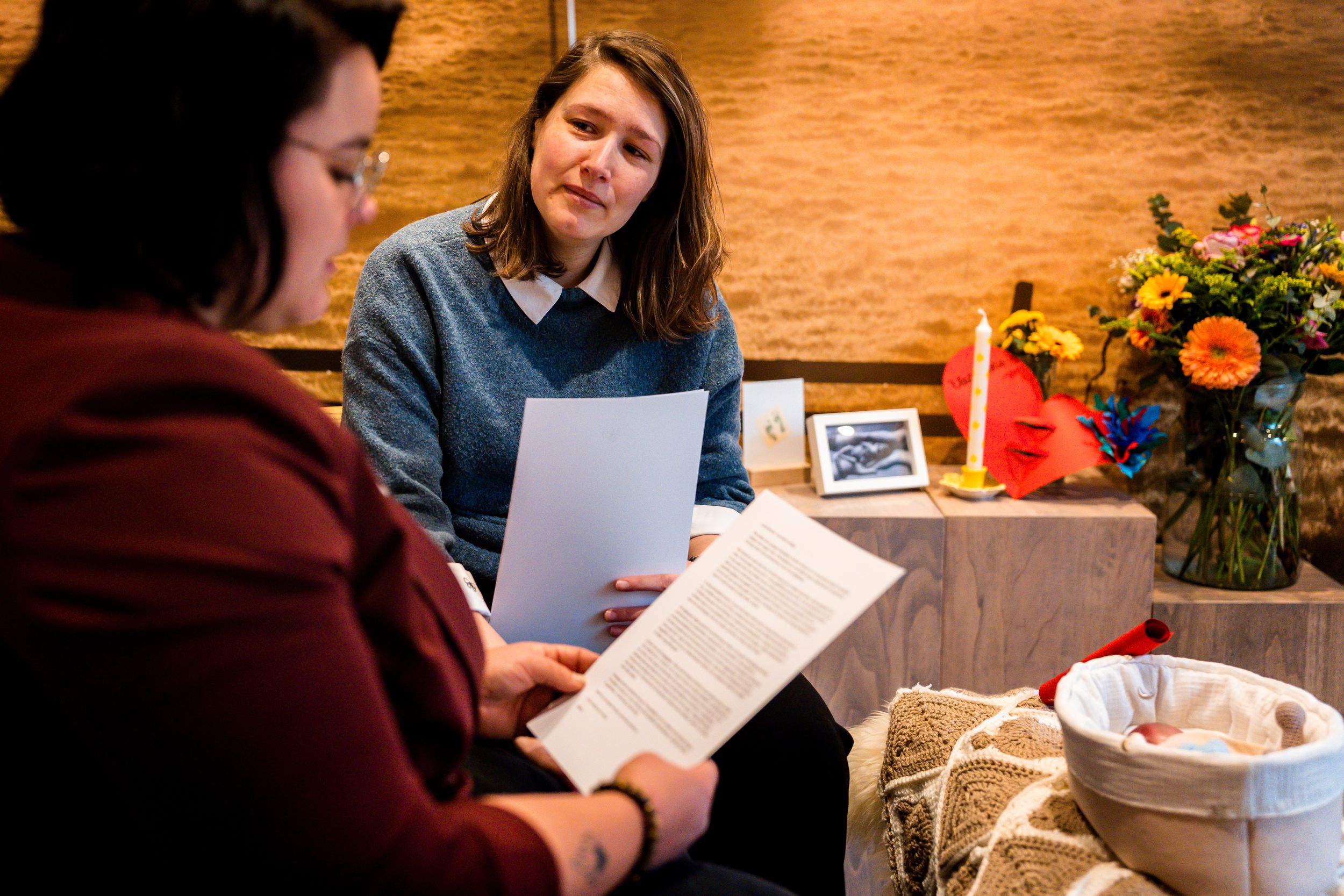A group gathers around a rustic wooden table with papers and documents for a collaborative meeting.