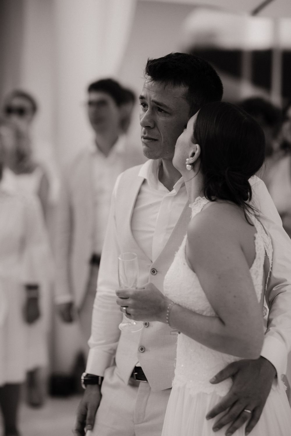 Pendant un cocktail de mariage au Cap d'Antibes une femme embrasse son mari qui pleure pendant un discours.
