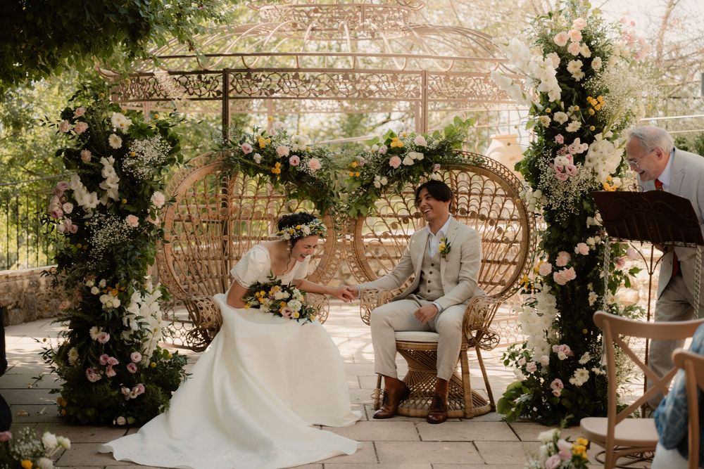 Photographe de Mariage au Mas des Cinq Fontaines - Scène d'un couple et du papa qui éclatent de rire pendant la cérémonie laïque très fleuri