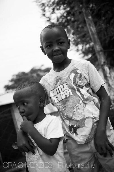 Two African boys posing together outdoors, older boy wearing a Battle Ready t-shirt.