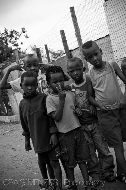 Black and white photo of a group of young African children posing together outdoors.