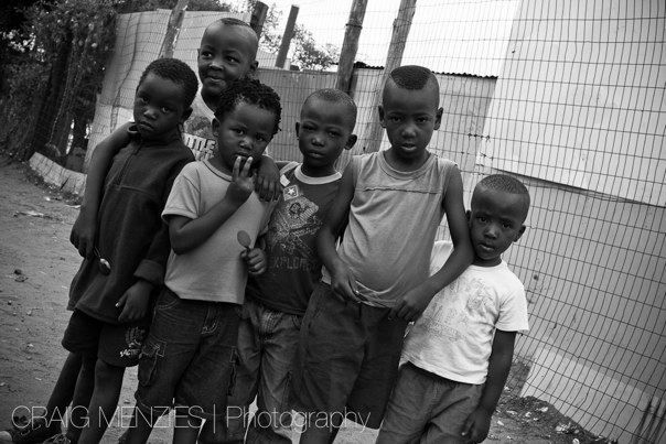 Group of young African boys posing together on a street in a black and white photograph.