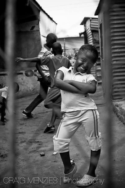 Joyful African child dancing and smiling on a township street in black and white.