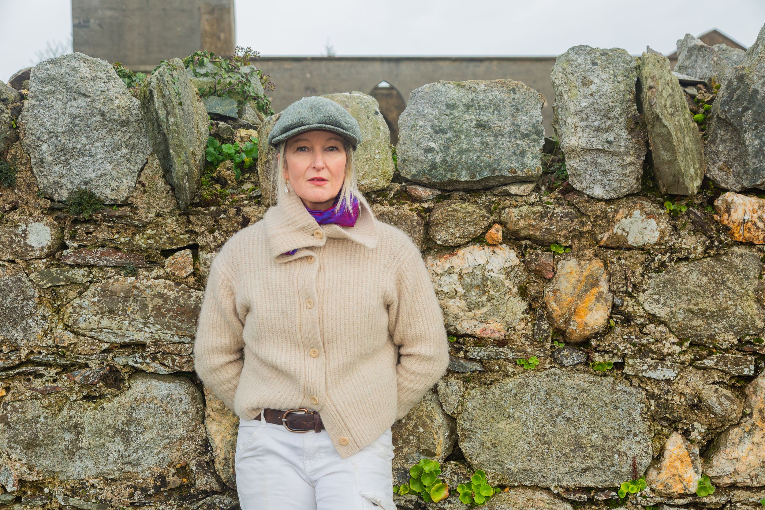 solo female traveller enjoying her private guided tour posing in front of an old stone wall.