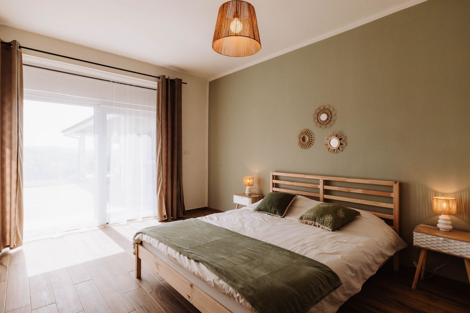 Modern bedroom interior with pendant lamp, white bedding, and olive green walls creating a cozy atmosphere.