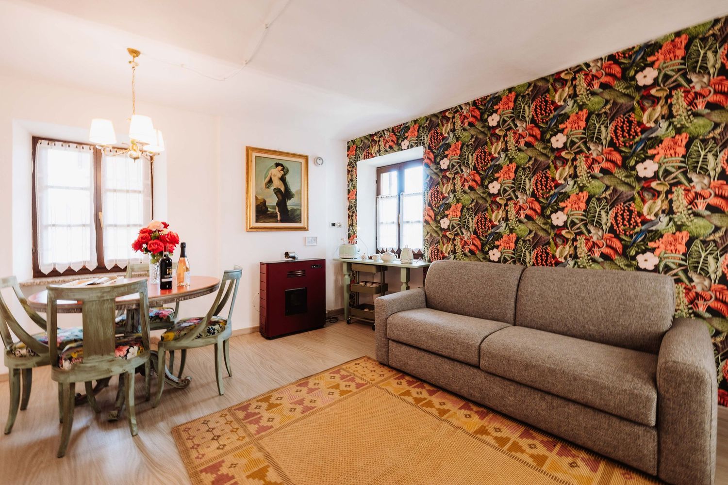 Living room with floral wallpaper, grey sofa, and natural light streaming through windows.