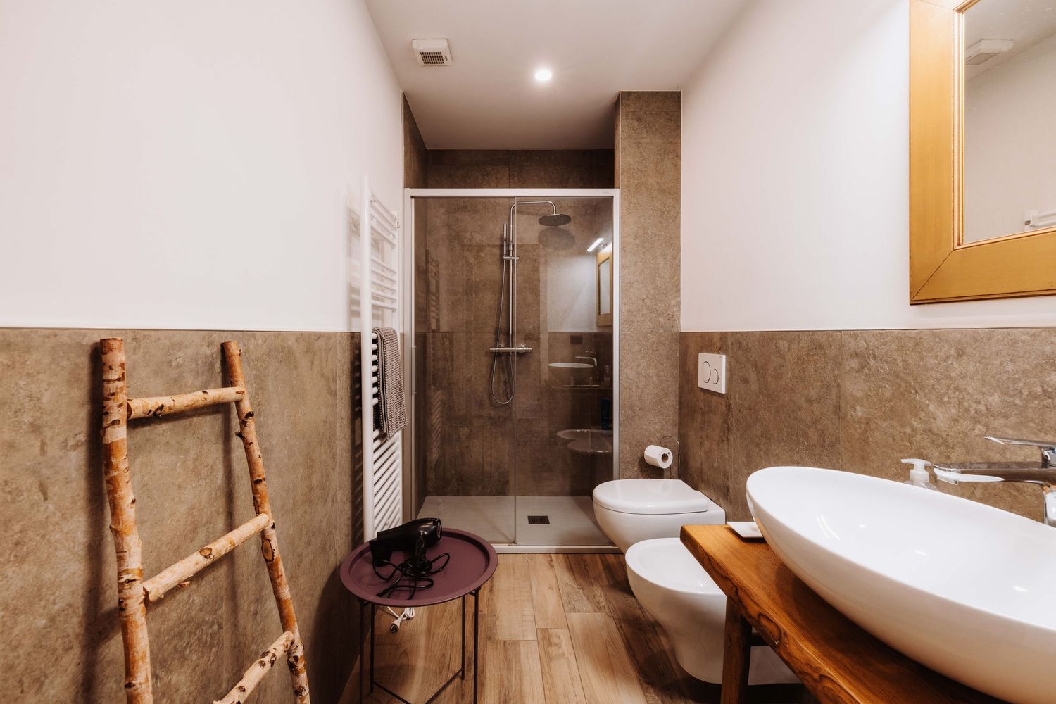 Contemporary bathroom featuring a freestanding white bathtub, natural stone walls, and warm lighting fixtures.