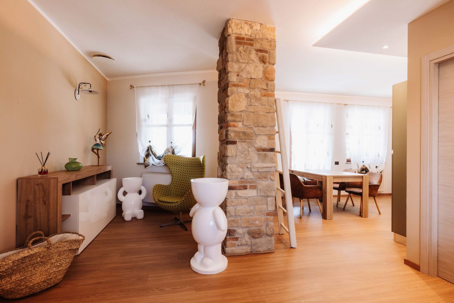 Modern interior design featuring exposed stone wall pillars and white walls with minimalist decor in a bright living space.